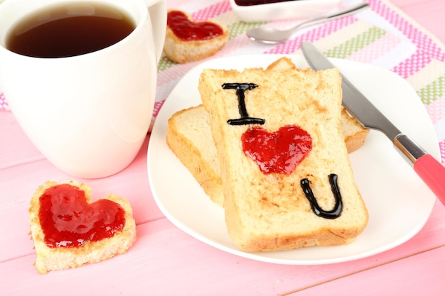 Köstlicher Toast mit Marmelade und Tasse Tee auf Tischnahaufnahme