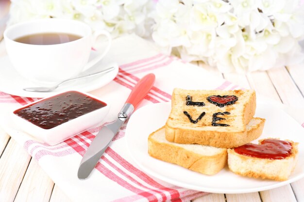 Köstlicher Toast mit Marmelade und Tasse Tee auf Tischnahaufnahme