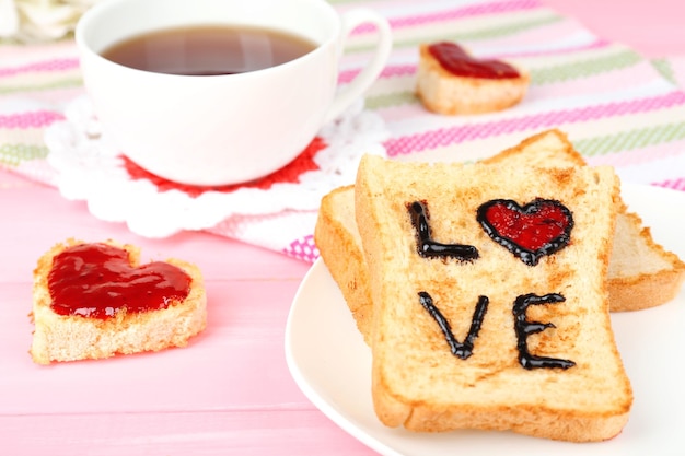 Köstlicher Toast mit Marmelade und Tasse Tee auf Tischnahaufnahme