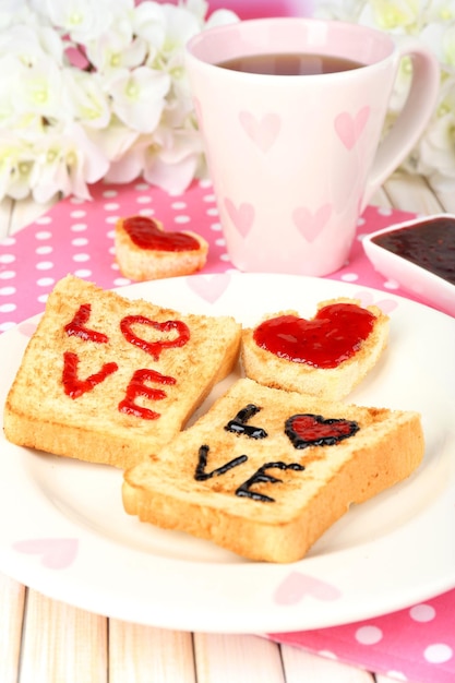 Köstlicher Toast mit Marmelade und Tasse Tee auf Tischnahaufnahme