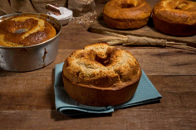 Köstlicher traditioneller Kuchen auf blauem Stoff mit anderen Kuchen und Rezeptelementen im Hintergrund, auf rustikalem Holz.