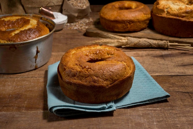 Köstlicher traditioneller Kuchen auf blauem Stoff mit anderen Kuchen und Rezeptelementen im Hintergrund, auf rustikalem Holz.