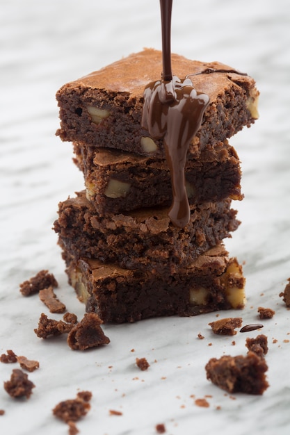 Köstlicher Turm aus klassischen Schokoladenbrownies mit Walnüssen und geschmolzener Schokolade.