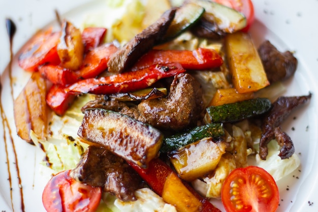 Köstlicher und gesunder Salat mit gegrilltem Gemüse auf einem weißen Teller in einem Restaurant