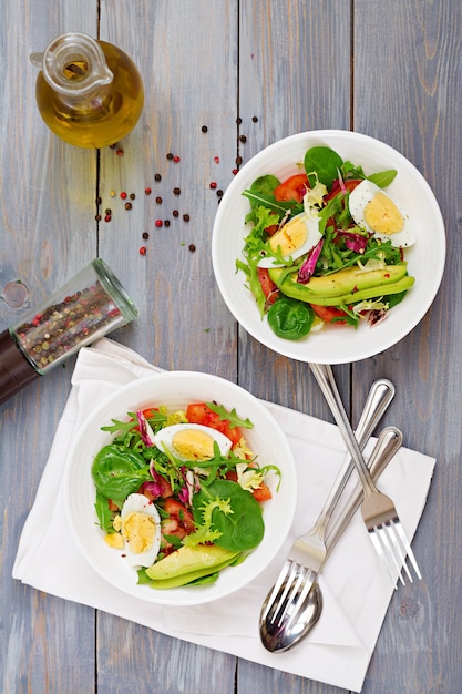 Köstlicher und leichter Salat aus Tomaten, Eiern und einer Mischung aus Salatblättern. Gesundes Frühstück. Ansicht von oben