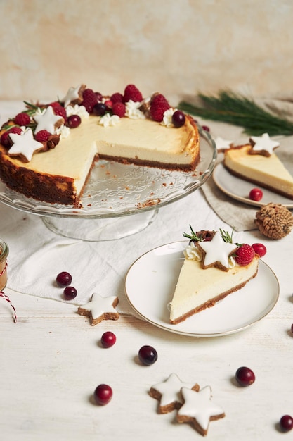 Köstlicher Weihnachtskäsekuchen mit Preiselbeeren und Kekssternen auf einem weißen Tisch