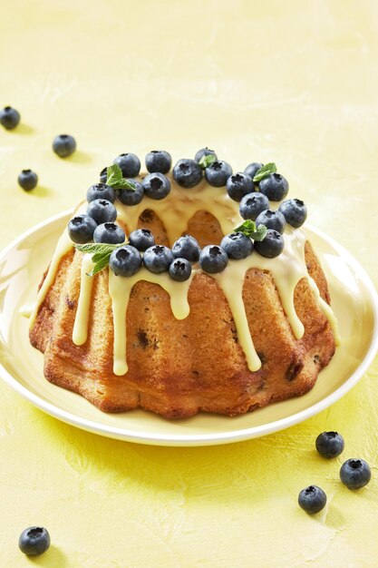 Köstlicher Zitronen-Blaubeer-Bundt-Kuchen mit Zuckerguss und Blaubeeren auf gelbem Hintergrund