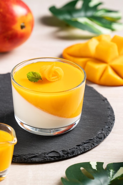 Köstlicher zweifarbiger Mango-Panna-Cotta-Mousse-Pudding auf Holztischhintergrund