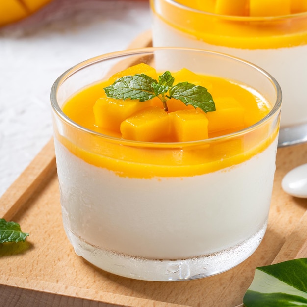 Köstlicher zweifarbiger Mango-Panna-Cotta-Mousse-Pudding auf weißem Tischhintergrund