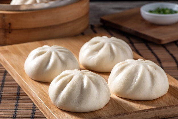 Köstliches Baozi, chinesisches gedämpftes Fleischbrötchen ist bereit, auf Servierteller und Dampfgarer zu essen, Nahaufnahme, kopieren Raumproduktdesignkonzept.