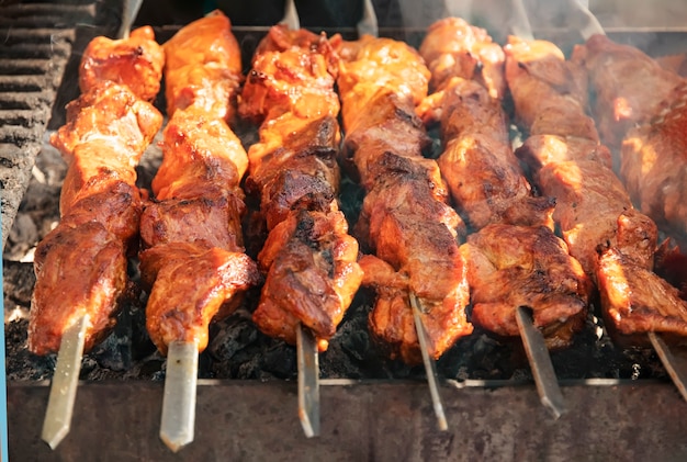 Köstliches Barbecue auf offenem Feuer gegrillt Schweinefleisch am Spieß gebraten für ein Sommerpicknick