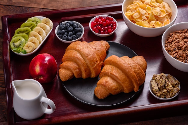 Köstliches Frühstück mit frischen Hörnchen und reifen Beeren auf einem schönen Holztisch