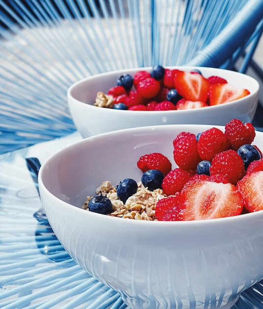 Köstliches Frühstück mit Müslijoghurt, Erdbeeren, Himbeeren und Heidelbeeren im Garten im Freien, gesunde Ernährung und Ernährung