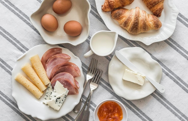 Köstliches hausgemachtes Frühstück, gekochte Eier, Schinken, Käse, Croissants auf dem Tisch.