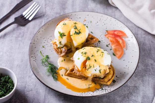 Köstliches hausgemachtes Frühstück mit Waffeln, Speck und Eiern Benedikt auf einem Teller