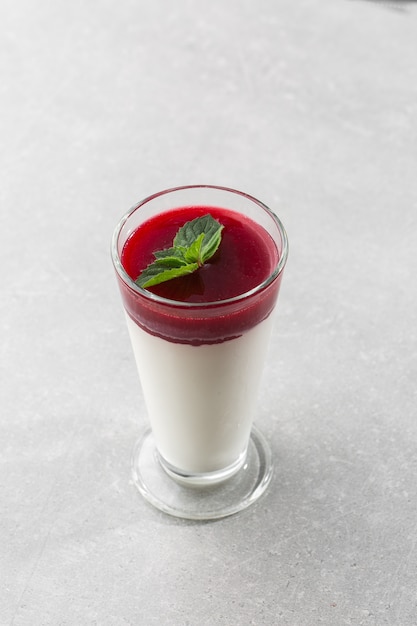 Köstliches italienisches Dessert Panna Cotta mit Beerensauce und Minze auf Grau