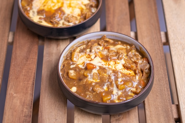 Köstliches japanisches Curry in Scheiben geschnitten mit Omelette-Reis und Gemüse, Curry-Reis in schwarzer Platte auf einem Holztisch mit Kopierraum.