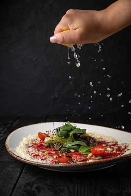 Köstliches Kalbscarpaccio auf einem Teller auf einem dunklen Holztisch