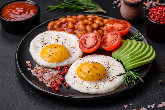 Köstliches, nahrhaftes englisches Frühstück mit Spiegeleiern, Tomaten und Avocado