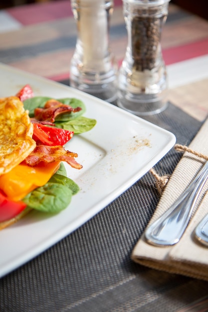 Köstliches Omelett aus nächster Nähe mit Käse, Grilltomate.Schinken, knusprigem Becon und Salat.