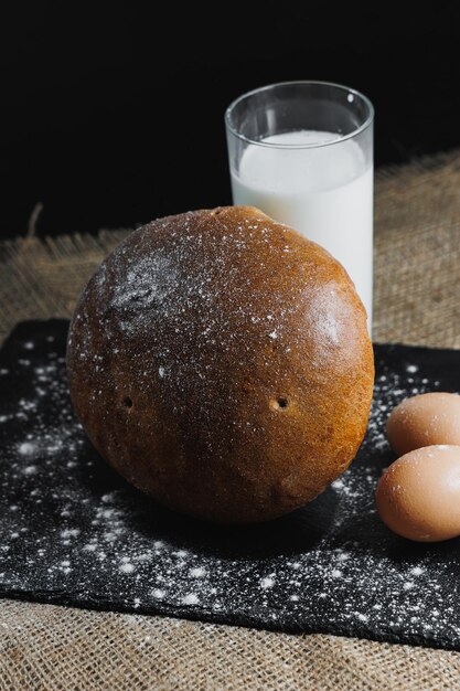 Köstliches rundes Roggenbrot mit Milch und Eiern auf dunklem Hintergrund Knuspriges frisches Brot