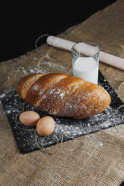 Köstliches rundes Roggenbrot mit Milch und Eiern auf dunklem Hintergrund Knuspriges frisches Brot