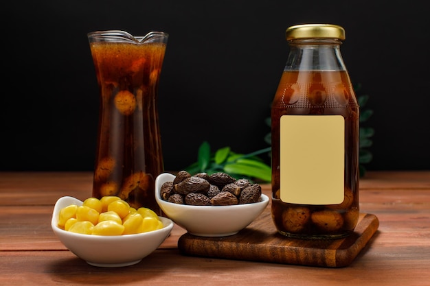 Köstliches Saftgetränk, serviert von einer Glasflasche auf dem Desserttisch mit einer Schüssel mit sauberem Bio-Ginkgo und Malva-Nuss als Rohstoffmischung für gesundes Getränk. Luxuriöse süße Diät mit zusätzlichen Nährstoffen