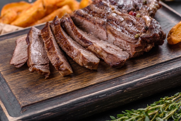 Köstliches saftiges frisches Rindersteak mit Gewürzen und Kräutern auf dunklem Betonhintergrund. Grillgerichte