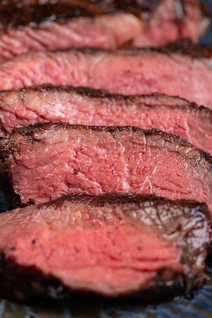 Köstliches saftiges gegrilltes Stück gegrilltes Steak mit Spinat und Saucen auf einem glänzenden blauen Teller Geschnittenes Steak Medium rare Ein herzhaftes Gourmet-Mittagessen Restaurantversorgung