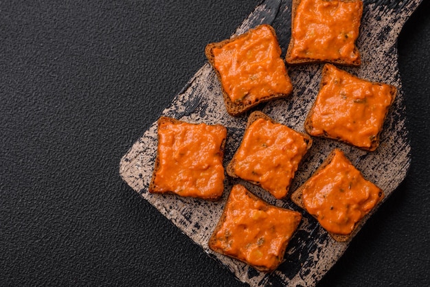 Köstliches Sandwich bestehend aus roter Toastsauce mit Salz, Gewürzen und Kräutern auf dunklem Betongrund