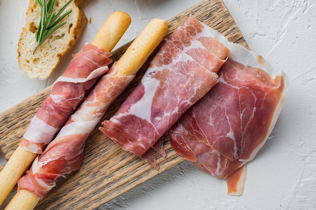 Köstliches Serrano-Schinken-Jamon-Set auf weißem Tisch, flach gelegen