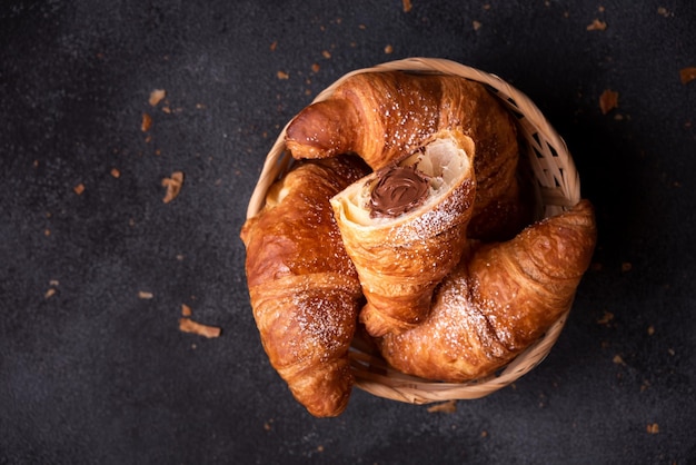 Köstliches süßes Croissant mit Schokolade auf dunklem Hintergrund