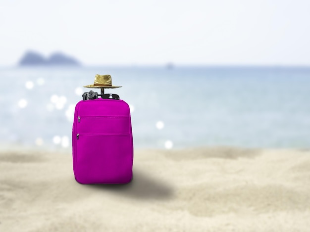 Koffer, Sonnenbrillen, Kamera und Strohhüte, am Strand und verschwommenes Meer. Bokeh das Sonnenuntergangslicht