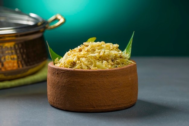 Kohlbraten oder Pfannengerichte für Kerala-Gerichte, die sehr schmackhafte vegetarische Speisen sind, die in einem Tongeschirr angeordnet sind, das auf grau strukturiertem Hintergrund platziert ist