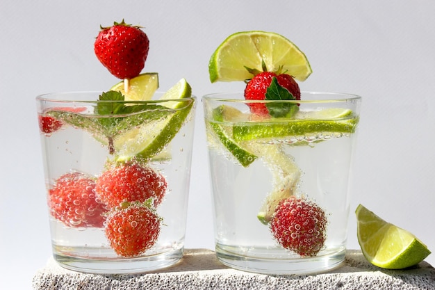 Foto kohlensäurehaltiges getränk mit limettenscheiben und erdbeeren in mit minzblättern dekorierten gläsern