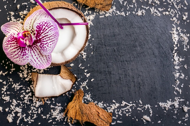 Kokosnüsse mit Kokosnussflocken und -orchidee auf dem grauen Stein backg