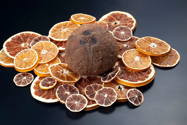 Kokosnuss liegt zwischen getrockneten Zitrusfrüchten auf einem dunklen Hintergrund