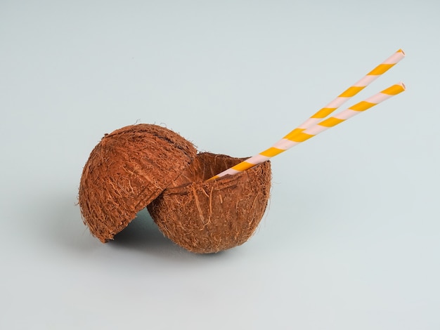 Kokosnuss mit einem Trinkrohr auf einem hellblauen Hintergrund, Nahaufnahme, Konzept, copyspace. schneiden Sie Kokosnuss mit zwei Rohren, Kokosmilchsaft