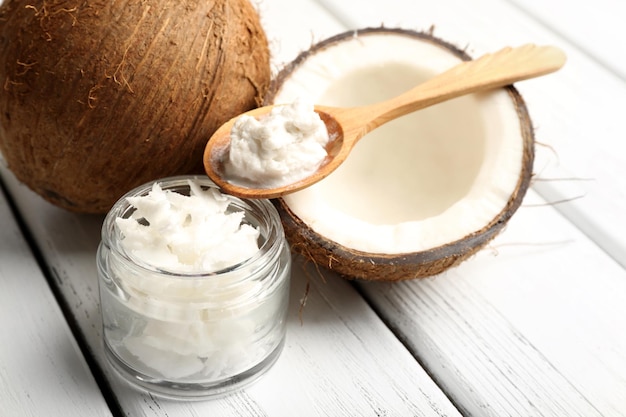 Kokosnuss mit Kokosnussöl im Glas auf hölzernem Hintergrund