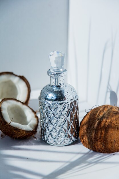 Kokosnuss- und Parfümflasche auf weißem Bacgkround mit Schatten