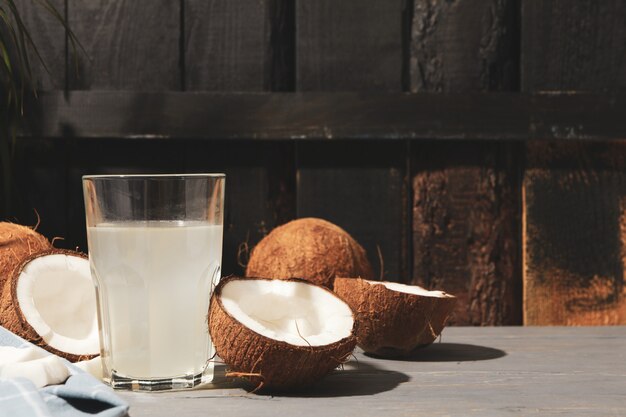 Kokosnuss und Wasser auf Holz, Platz für Text. Tropische Frucht