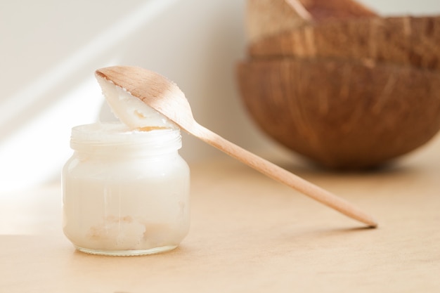 Kokosöl in Glas und Holzlöffel. Naturkörper, Gesicht, Haarpflegekonzept.