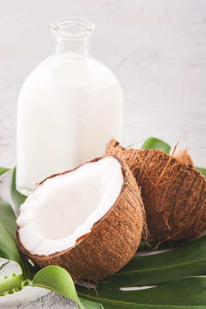 kokosöl in glasflasche mit frischer nuss und monsterblatt