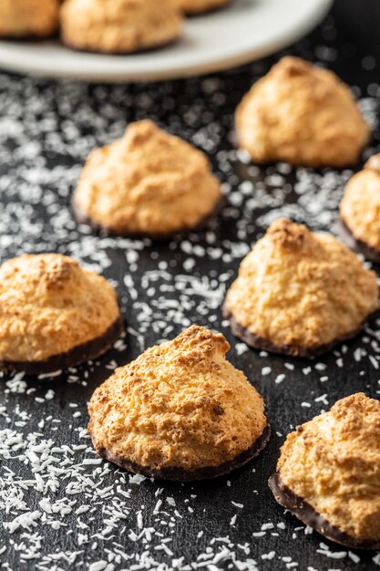 Foto kokosplätzchen mit schokolade und kokosraspeln auf schwarzem tisch