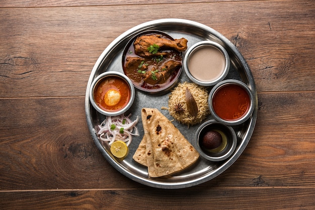 Kolhapuri chicken thali ist eine beliebte indische, asiatische speisenplatte bestehend aus geflügelfleisch, eiercurry mit chapati, reis, salat und süßem gulab jamun