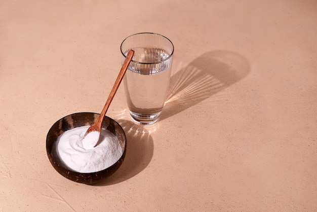 Kollagenproteinpulver in einer Schüssel und ein Glas Wasser auf beigenem Hintergrund Ein Nahrungsergänzungsmittel für Haut und Gelenke Kreatives Foto