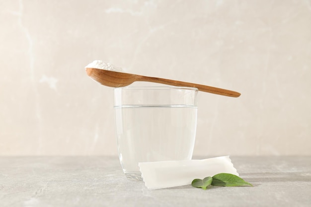Kollagenpulver in einem Holzlöffel mit einem Glas Wasser