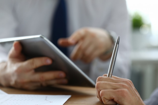 Kollege mit moderner Tablette und Zeigen auf Schirm mit dem Finger.