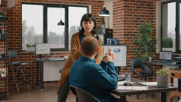 Kollegen arbeiten zusammen an Geschäftsprojekten und sprechen über Marketingstrategie am Schreibtisch. Arbeitskollegen entwickeln Ideen zum Entwerfen von Tarifdiagrammen auf dem Computer, um die Datenanalyse zu planen.
