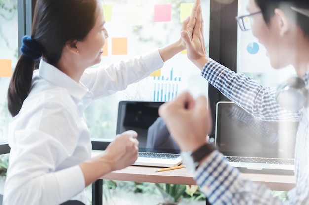 Kollegen, die im Schreibtisch-Büro High-Five geben